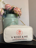 White pouch with 'A Rose & Me' branding next to a vase with flowers on a light surface.